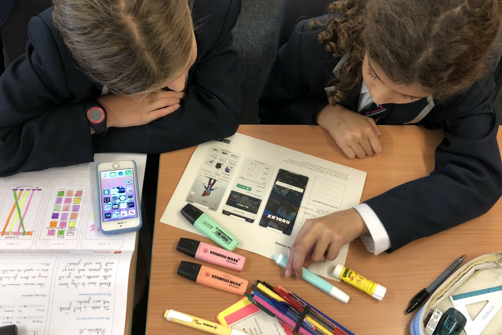 Two girls complete the worksheet on how apps make money